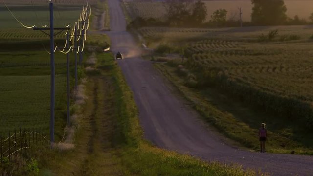 Slow motion static view of woman walking up dirt road.