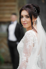 Naklejka premium Beautiful brunette bride walking down old street, while the groo