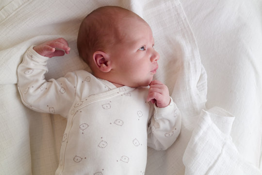 Newborn baby boy on white cloth diaper thinking cute pose