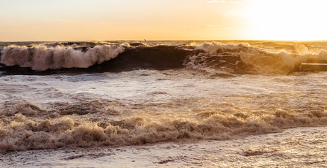 biga waves crashing on the beach at sunset