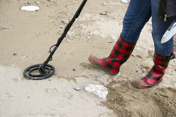 Searching for a lost jewelry on the beach using a metal detector