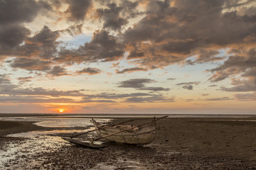 Old wooden sailor boat stranded on a sunset beach
