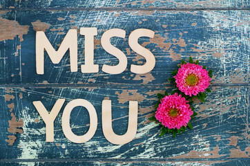 Miss you written with wooden letters on rustic surface and pink daisy flowers
 - obrazy, fototapety, plakaty