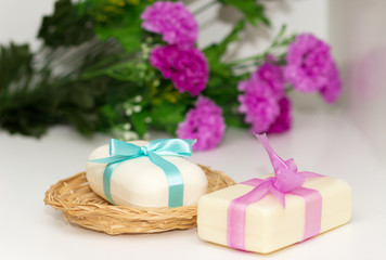 Fototapeta na wymiar Two pieces of soap with a basket with a bow and flowers