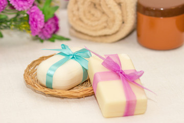 Two pieces of soap with a basket with a bows , flowers , towel a