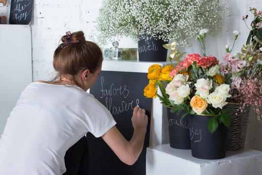Florist writing on black graphit desk, yellow and white flowers