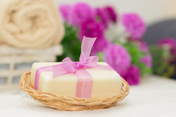 Obraz na płótnie Canvas Big piece of beige soap in busket, witn purple bow, flowers on b