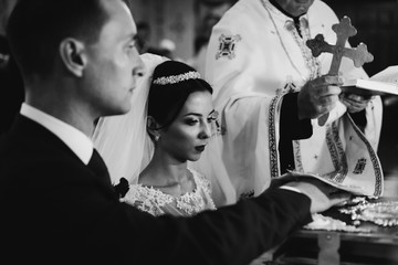 Sensual emotional bride and groom taking vows at the bible in ch