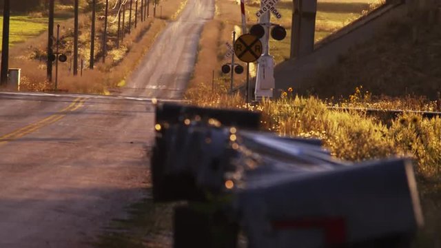Static shot of country road, mailboxes and rail road crossing.