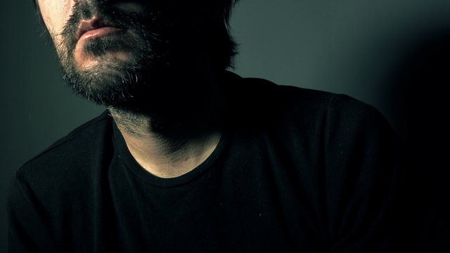 Psychotic bearded man with mental problems, low key portrait in dark room