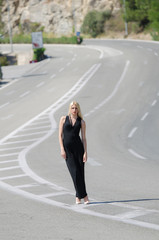Outstanding model with a slim body do a fashion shooting on the high speed road wearing a black neck jumpsuit