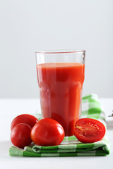 Fresh red tomatoes in basket and tomato juice in glass on white