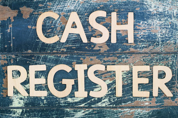 Cash register written with wooden letters on rustic surface
