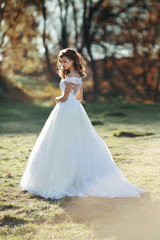 Fototapeta na wymiar Sunlit gorgeous brunette bride in white dress posing in sunset f
