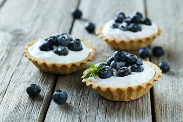 Dessert tartlets with blueberries on grey wooden background