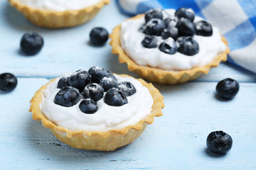 Dessert tartlets with blueberries on blue wooden background