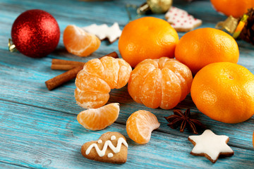 Ripe mandarins with gingerbread cookies on a blue wooden table