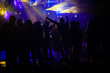Silhouette of people dancing and talking in a music festival