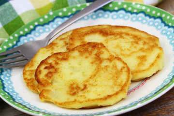 Golden potato fritters on plate, closeup
