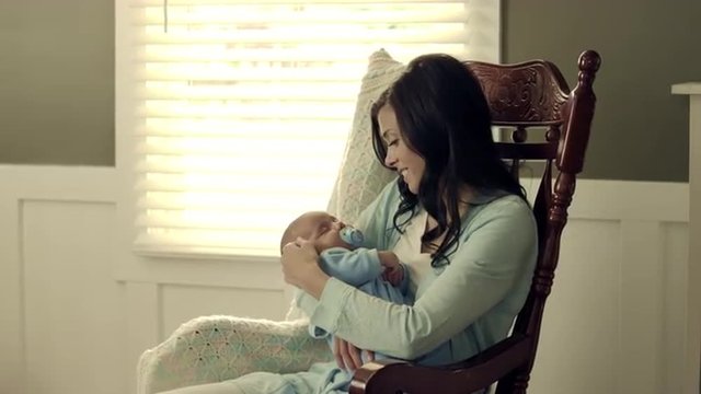 Royalty Free Stock Footage of Mother rocking her baby to sleep in a rocking chair.