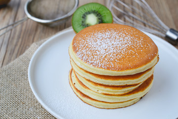 icing sugar on stack of pancake on white plate and sackcloth wit