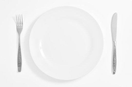 Empty plate, fork and knife isolated on white