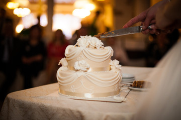 Tasty and delicious brown and white tiered wedding cake carved a