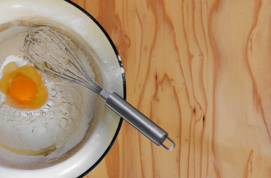 broken egg in flour and whisk on a wooden table. top view closeup. Copy space. Free space for text