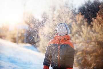 Cute little boy, playing with snow in the park in sunny day,  wi