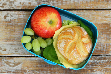 School lunch box with cheese sandwich, red apple and grapes
