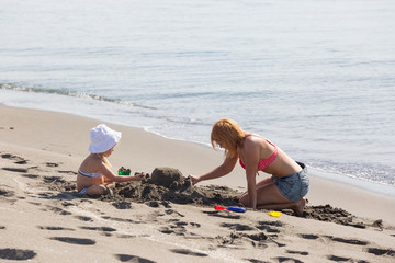 Mom and daughter are building a sand castle