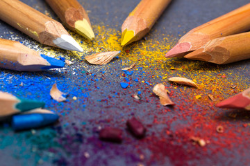 Multicoloured pencils, shavings and fragments of broken cores on grey background