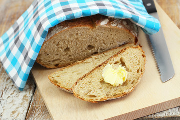Slices of freshly baked rye bread and butter on wooden board
