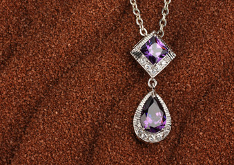Fototapeta na wymiar jewelry pendant with diamonds on brown sand background, with cop
