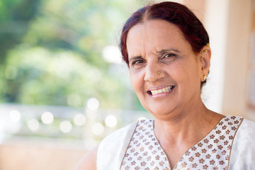 Closeup portrait, senior woman smiling on isolated outdoors outside background, positive emotion facial expression feelings