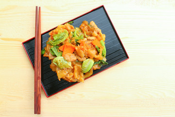 Noodle in black plate with chopsticks on wooden background