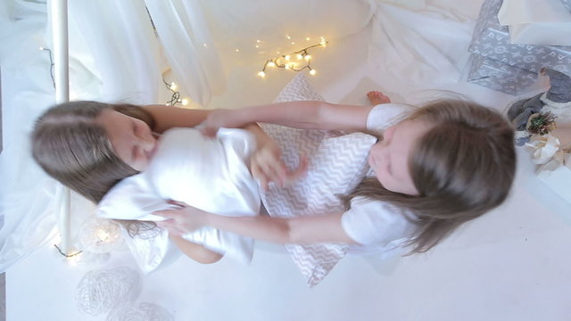Little girls dressed in white pillow fight