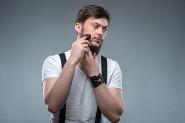 Attractive young strong man is shaving himself 