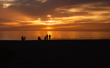 Fototapeta na wymiar Silhouettes of people at sunset on beach