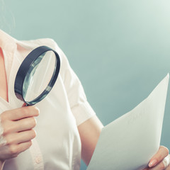 woman uses magnifying glass to check contract