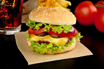 Menu of cheeseburger,french fries,glass of cola on wooden desk on black.