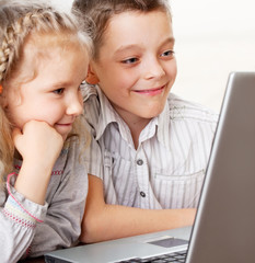 Happy kids playing laptop at home