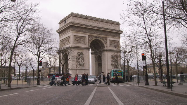 People crossing the street at the the Arc de Triomphe in Paris France.