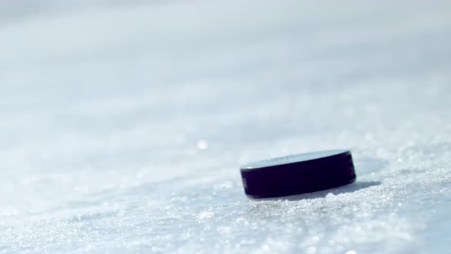 Hockey puck falling onto ice and being picked up by a gloved hand.