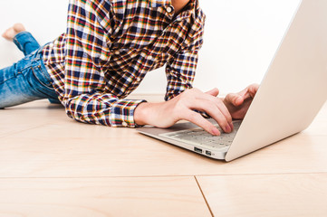 部屋の床でノートパソコンを操作している男性