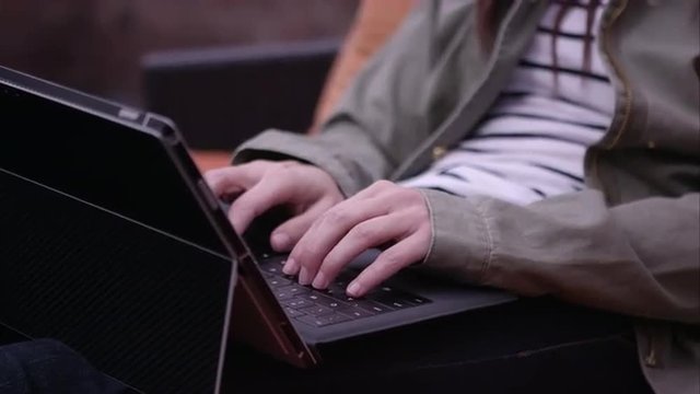 Panning view of woman typing the running fingers through hair.