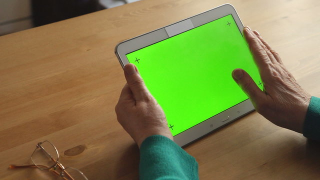 A white Tablet PC in a adult woman hands (green screen)
