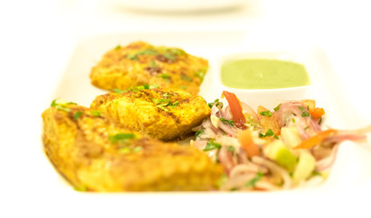 Spicy Indian fish tikka masala with flavored curd and garnish. 