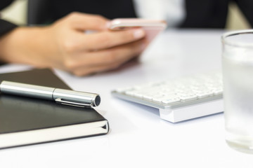 soft focus of Hand of a businessman holding a phone to work. And a keyboard on a notebook on the table.Vintage Style.