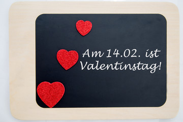 drei rote Herzen und Text auf einer Tafel